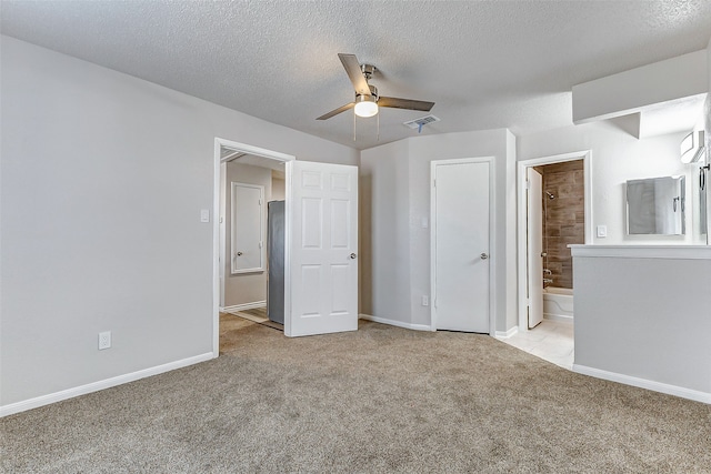 unfurnished bedroom with ensuite bath, ceiling fan, light colored carpet, and a textured ceiling