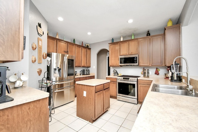 kitchen with light tile patterned floors, stainless steel appliances, a kitchen island, and sink