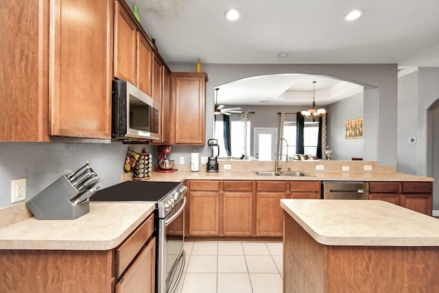 kitchen featuring ceiling fan with notable chandelier, a raised ceiling, sink, light tile patterned floors, and stainless steel appliances