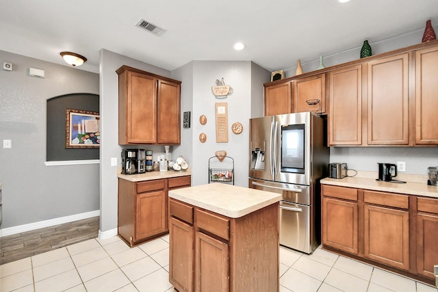 kitchen with stainless steel refrigerator with ice dispenser, light tile patterned floors, and a kitchen island