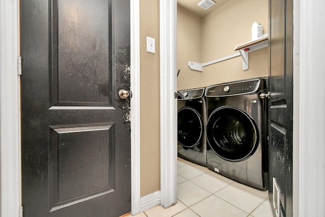 clothes washing area featuring light tile patterned flooring and washer and dryer