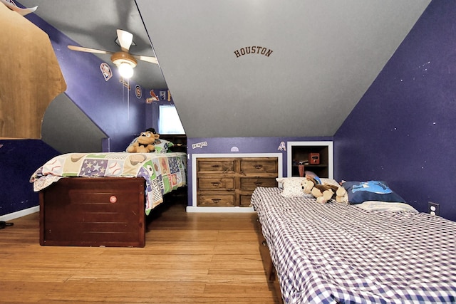 bedroom with ceiling fan, hardwood / wood-style floors, and vaulted ceiling