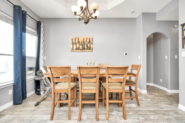 dining room with a tray ceiling and a notable chandelier