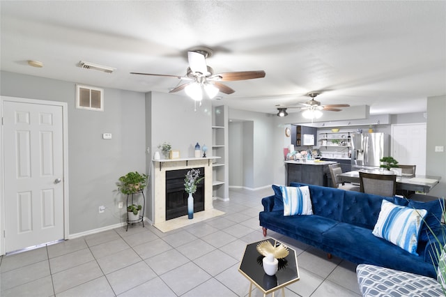 tiled living room featuring a high end fireplace, a textured ceiling, and ceiling fan