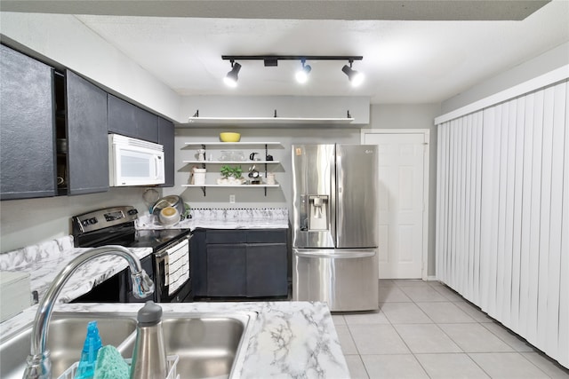 kitchen featuring sink, rail lighting, light stone counters, light tile patterned floors, and appliances with stainless steel finishes