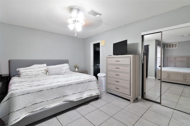 tiled bedroom featuring ceiling fan, ensuite bath, and a closet