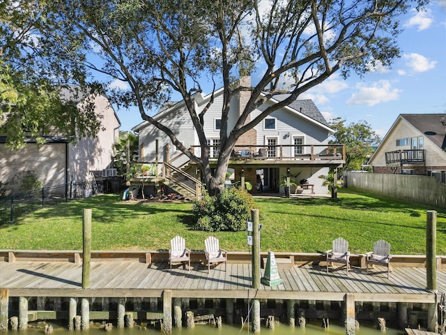 dock area featuring a deck with water view, a yard, and an outdoor fire pit