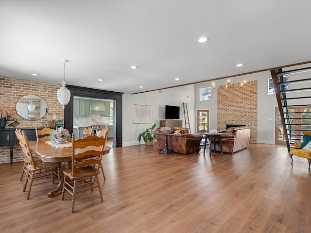 dining space featuring a fireplace, light hardwood / wood-style floors, an inviting chandelier, and ornamental molding