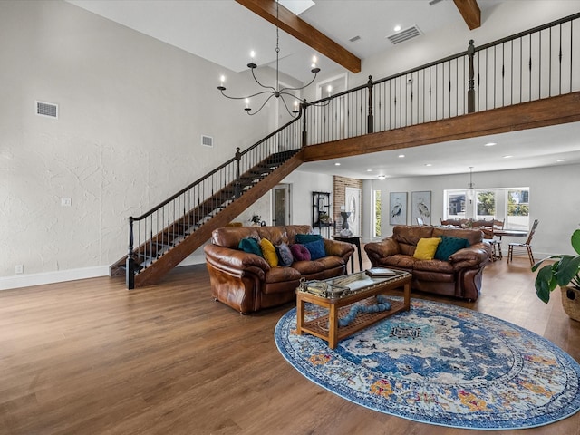 living room with a chandelier, beam ceiling, hardwood / wood-style flooring, and a high ceiling