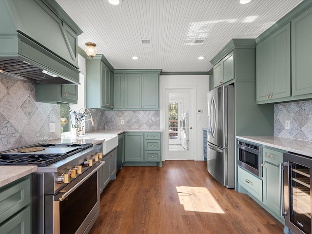 kitchen featuring backsplash, stainless steel appliances, beverage cooler, green cabinetry, and dark hardwood / wood-style floors