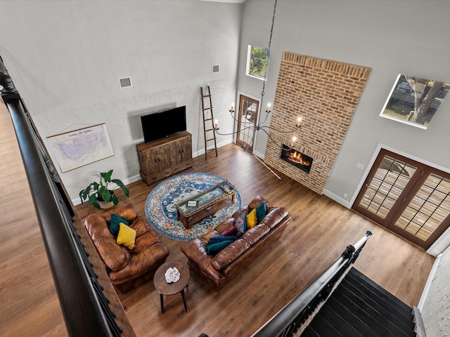 living room featuring hardwood / wood-style floors, a high ceiling, and a brick fireplace