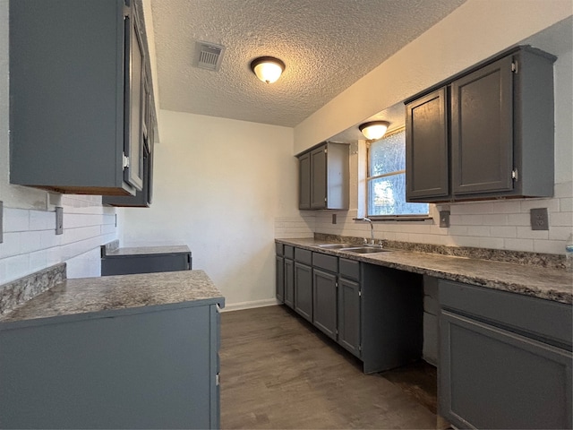 kitchen featuring gray cabinets, tasteful backsplash, dark wood-type flooring, and sink