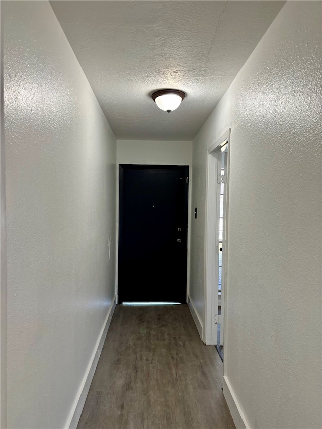 hall featuring a textured ceiling and dark wood-type flooring