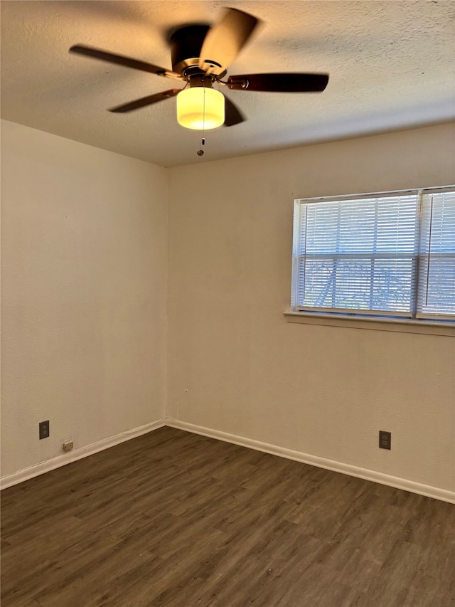 empty room with ceiling fan, dark wood-type flooring, and a textured ceiling