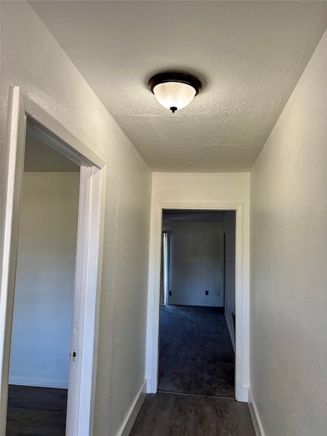 hall featuring a textured ceiling and dark wood-type flooring