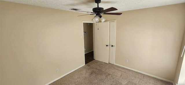 unfurnished bedroom featuring ceiling fan, a textured ceiling, and dark colored carpet