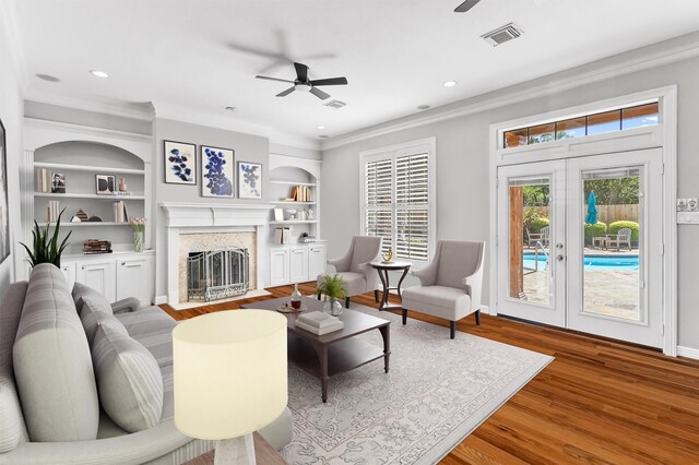 living room featuring a high end fireplace, french doors, ceiling fan, crown molding, and hardwood / wood-style floors