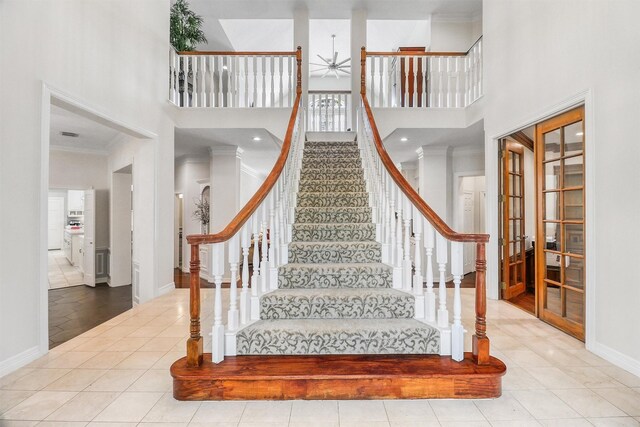 stairway with ceiling fan, crown molding, a high ceiling, and tile patterned flooring