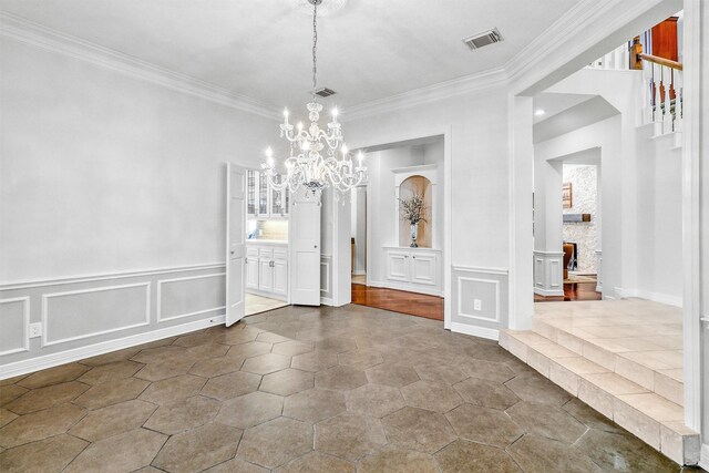 unfurnished dining area featuring a notable chandelier, ornamental molding, and a fireplace