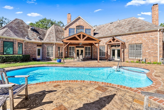 view of swimming pool featuring a patio area, an in ground hot tub, and french doors