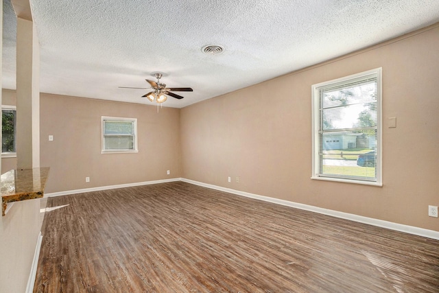 empty room with ceiling fan, dark wood-type flooring, and a textured ceiling