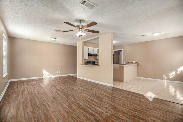 unfurnished living room with ceiling fan, light hardwood / wood-style floors, sink, and a textured ceiling