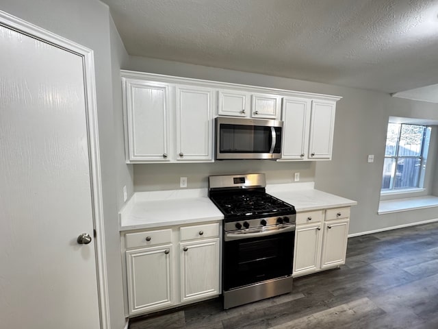 kitchen featuring a textured ceiling, stainless steel appliances, white cabinetry, and dark wood-type flooring