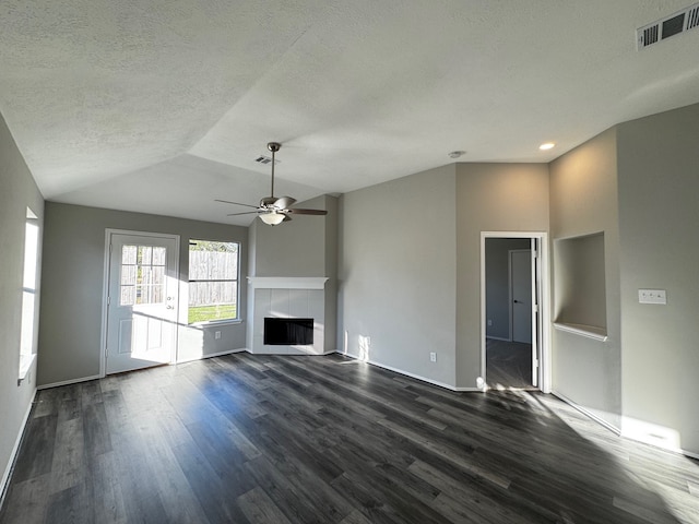 unfurnished living room featuring vaulted ceiling, ceiling fan, a textured ceiling, dark hardwood / wood-style flooring, and a tiled fireplace