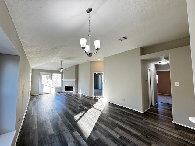 unfurnished living room featuring a textured ceiling, lofted ceiling, dark wood-type flooring, and a tile fireplace