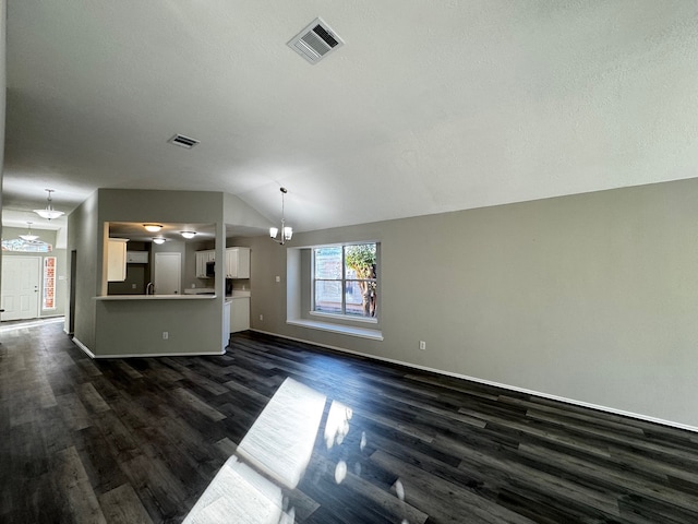 unfurnished living room with a notable chandelier, dark wood-type flooring, and vaulted ceiling