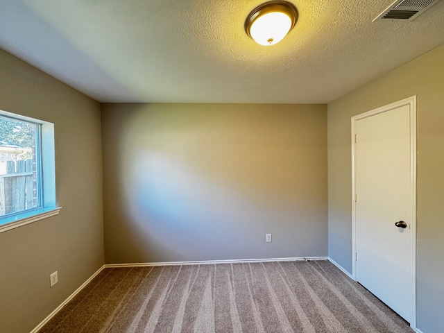 carpeted empty room featuring a textured ceiling