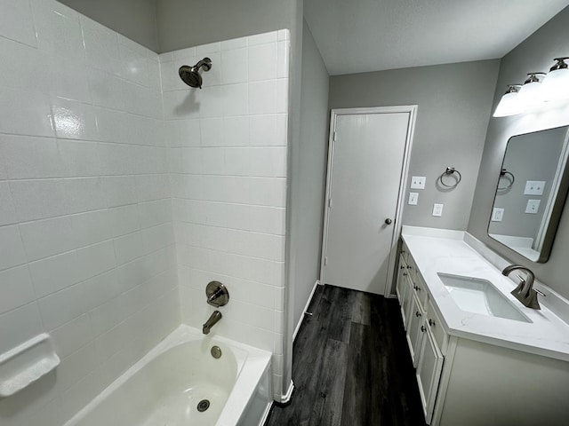 bathroom with hardwood / wood-style floors, vanity, and tiled shower / bath combo