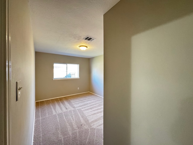 carpeted empty room featuring a textured ceiling