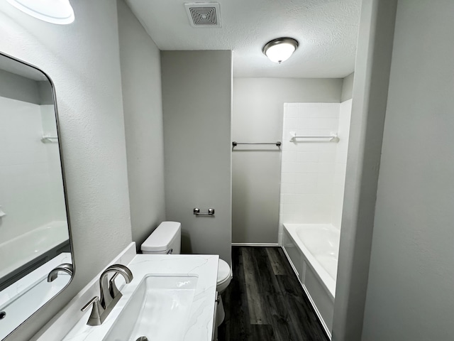 full bathroom featuring hardwood / wood-style floors, shower / bath combination, a textured ceiling, toilet, and vanity