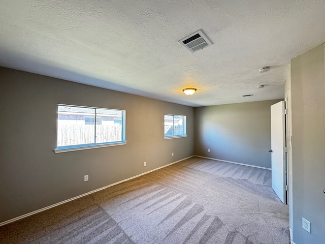 carpeted empty room featuring a textured ceiling