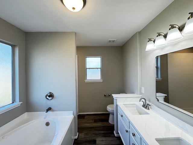 bathroom with a washtub, vanity, a textured ceiling, hardwood / wood-style floors, and toilet