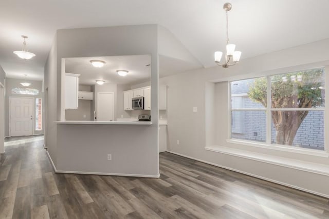 kitchen with white cabinets, kitchen peninsula, a notable chandelier, and dark hardwood / wood-style floors