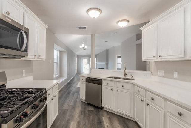 kitchen featuring white cabinets, appliances with stainless steel finishes, lofted ceiling, sink, and a notable chandelier