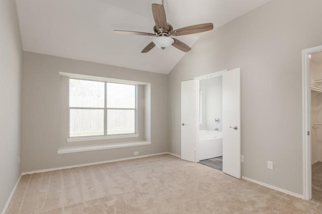 unfurnished bedroom with a spacious closet, light carpet, ensuite bathroom, ceiling fan, and lofted ceiling