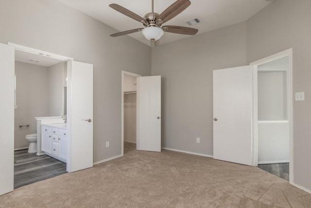 unfurnished bedroom with ceiling fan, ensuite bath, carpet flooring, a spacious closet, and a closet