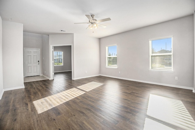 unfurnished room with ceiling fan, dark wood-type flooring, and a healthy amount of sunlight