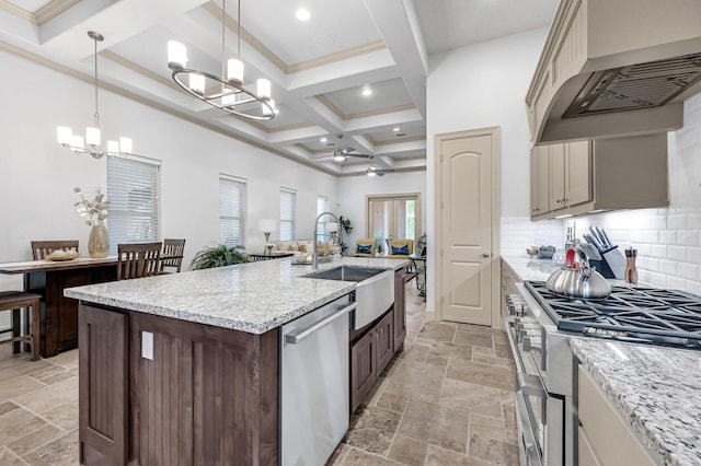 kitchen featuring custom exhaust hood, ceiling fan with notable chandelier, sink, appliances with stainless steel finishes, and decorative light fixtures