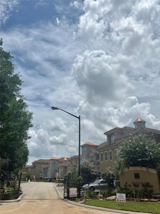 view of road featuring street lighting, a residential view, curbs, and a gated entry