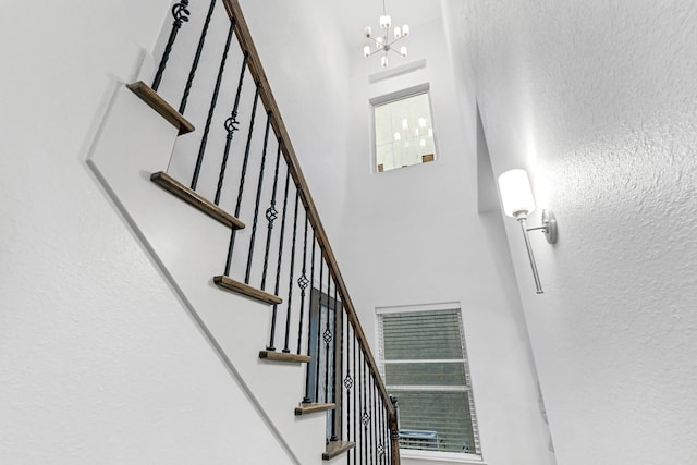 stairway featuring a high ceiling and a notable chandelier