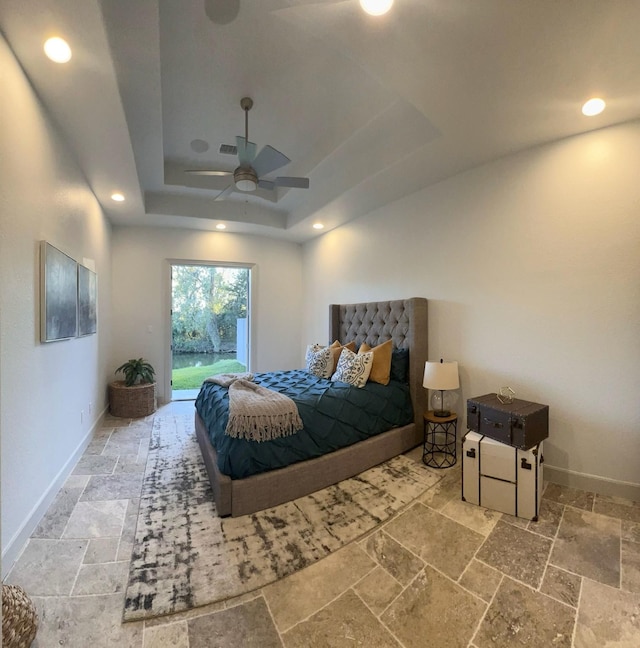 bedroom with recessed lighting, baseboards, access to outside, a tray ceiling, and stone tile flooring