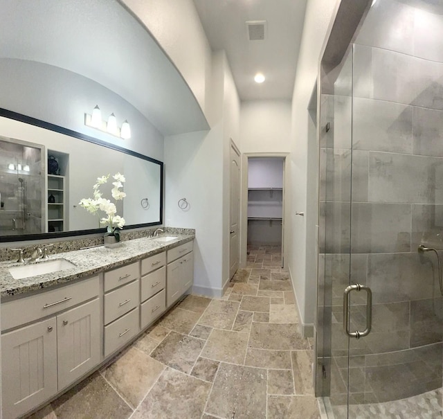 bathroom with vanity, vaulted ceiling, and a shower with door