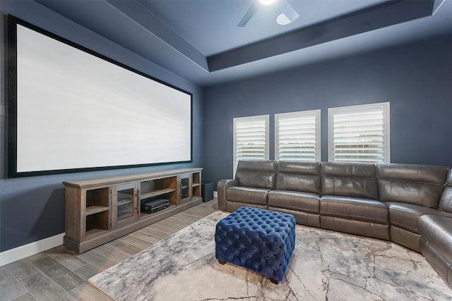 cinema featuring hardwood / wood-style flooring, ceiling fan, and a tray ceiling