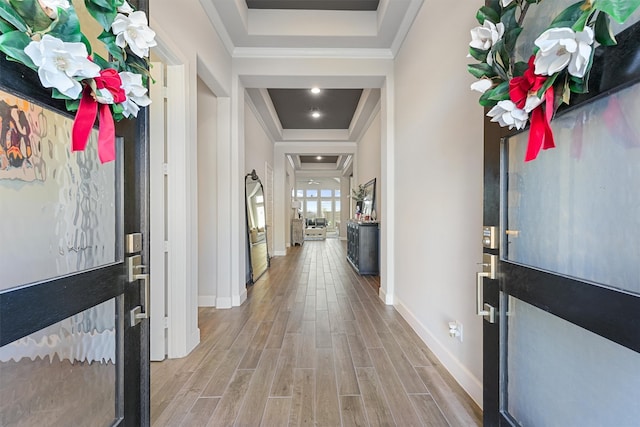 entrance foyer with a tray ceiling, light hardwood / wood-style floors, and ornamental molding