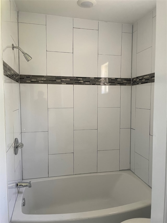 bathroom with toilet and tiled shower / bath