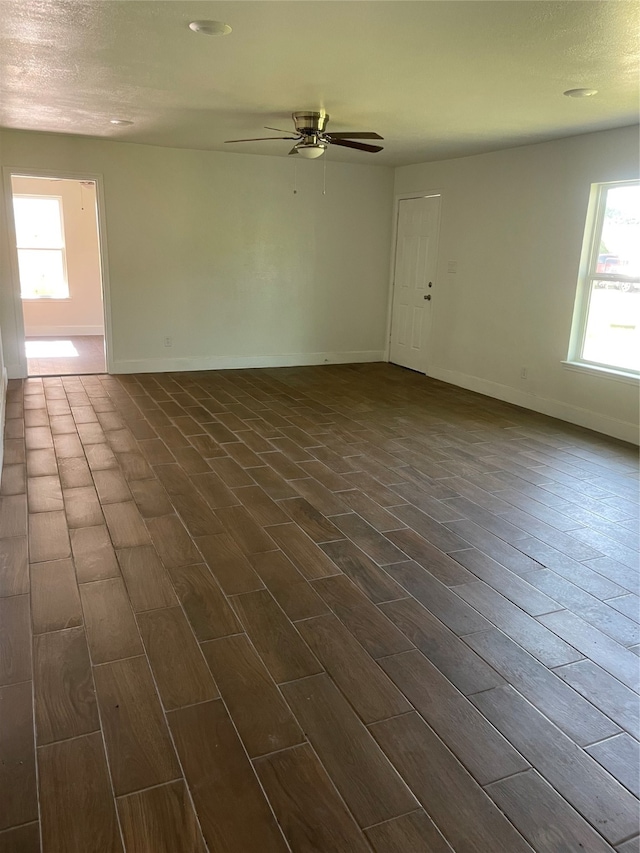 unfurnished room featuring dark hardwood / wood-style floors, ceiling fan, and a healthy amount of sunlight